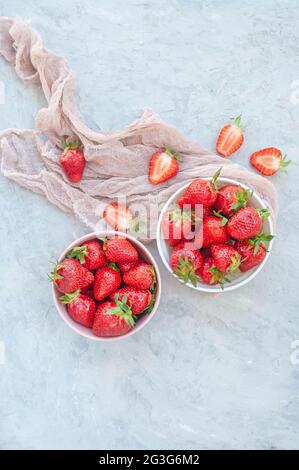 Piatto di fragole dolci fresche mature in ciotole bianche e rosa su sfondo grigio. Foto Stock