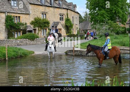 Cavalli su un hack nel pittoresco villaggio di Cotswold di Lower Slaughter nel River Eye che scorre attraverso il centro del villaggio. Foto Stock