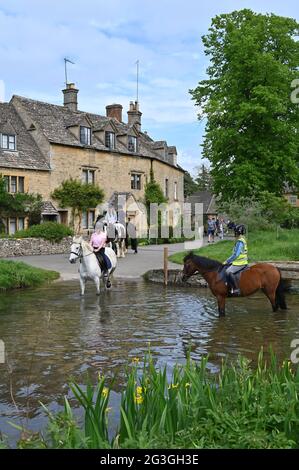Cavalli su un hack nel pittoresco villaggio di Cotswold di Lower Slaughter nel River Eye che scorre attraverso il centro del villaggio. Foto Stock
