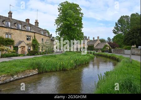 Una fila di case si trova vicino al River Eye che scorre attraverso il pittoresco villaggio di Lower Slaughter, una popolare destinazione turistica in questa parte o Foto Stock