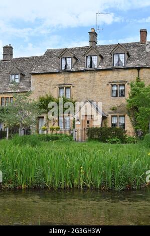 Una fila di case si trova vicino al River Eye che scorre attraverso il pittoresco villaggio di Lower Slaughter, una popolare destinazione turistica in questa parte o Foto Stock