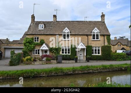 Una fila di case si trova vicino al River Eye che scorre attraverso il pittoresco villaggio di Lower Slaughter, una popolare destinazione turistica in questa parte o Foto Stock