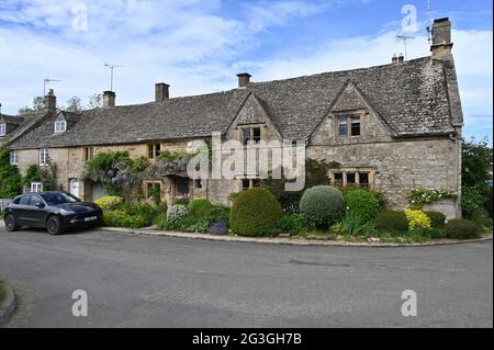 Glicine in fiore che cresce all'esterno di una casa a Bledington, Gloucestershire Foto Stock