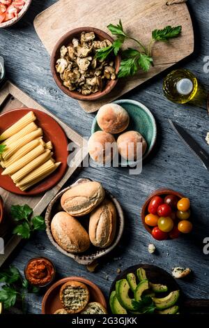 vista ad alto angolo di alcuni ingredienti diversi per preparare antipasti vegani, come panini, funghi cotti, animaletti, avocado a fette o che Foto Stock