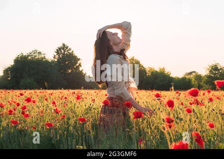 Giovane donna che balla sul campo di papavero Foto Stock