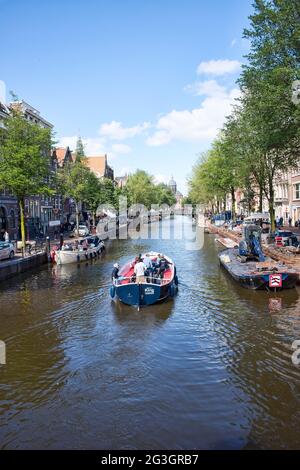 Amsterdam, Paesi Bassi - 12 luglio 2017: I passeggeri di un giro in barca attraverso i 165 canali di Amsterdam, uno dei modi migliori per vedere la città. Foto Stock