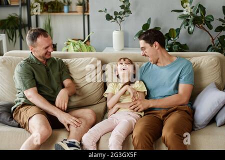 Buona famiglia di tre persone che si divertono sul divano in camera Foto Stock