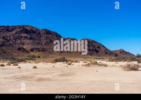 Catena montuosa nel deserto del Mojave con un letto di lago asciutto Foto Stock