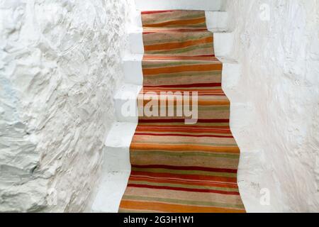 Scale coperte da moquette tradizionale . Pareti bianche e scala. Ingresso alla cantina Foto Stock