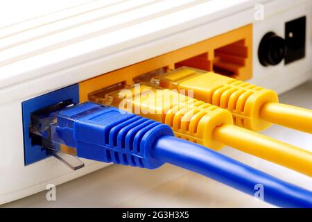 Primo piano su tre cavi di rete collegati alle porte WAN e LAN del router Foto Stock