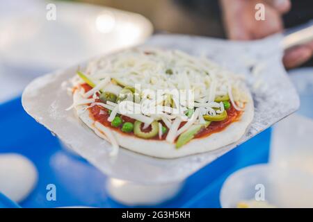 Preparare la pizza fatta in casa prima di cuocere la pasta per pizza con cibo tradizionale italiano con verdure e formaggio Foto Stock