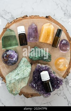 Closeup di bottiglie di olio essenziale, cristalli colorati e gemme su piastra di legno Foto Stock