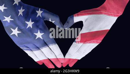 Composizione di due mani che tengono le mani decorate con bandiera americana che fa la forma del cuore su nero Foto Stock