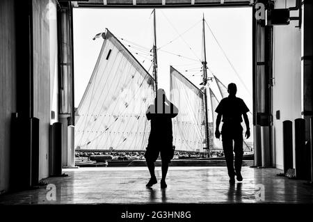 Immagine monocromatica di persone che guardano una goletta di alto mare che naviga alla regata di Halifax Tall Ships. Foto Stock