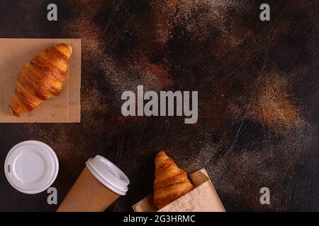 Caffè da gustare in una tazza di carta con croissant, vista dall'alto. Foto Stock