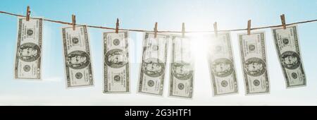 Banner sul concetto di riciclaggio di denaro. Panoramica di US dollards appesi ad asciugare per lavanderia su stendibiancheria. Foto Stock