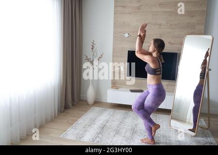 Giovane donna in abbigliamento sportivo che fa yoga mentre si rilassa a casa Foto Stock