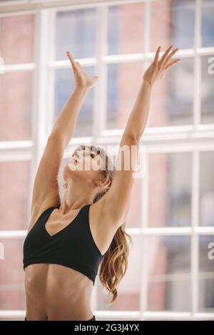 Donna che fa le mani si allunga nella sala fitness. Donna con braccia allungate durante la lezione di yoga. Foto Stock