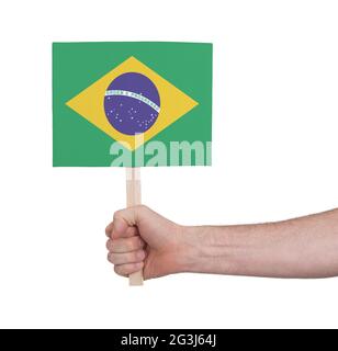 Mano che tiene la piccola carta - bandiera del Brasile Foto Stock