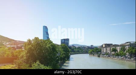 La moderna città di Tbilisi sullo sfondo del cielo blu con il fiume Kura nel mezzo Foto Stock