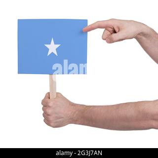 Mano che tiene la piccola carta - bandiera della Somalia Foto Stock