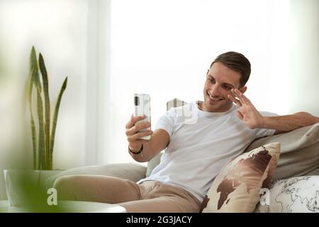 giovane che fa una videochiamata a casa agitando sul telefono cellulare Foto Stock
