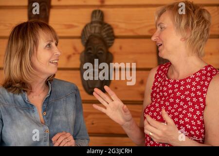Due donne di 55 anni si guardano l'una all'altra e ridono molto e parlano Foto Stock