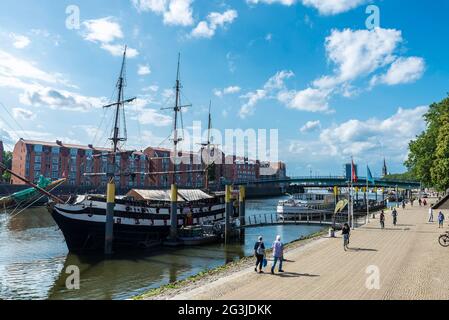 Brema, Germania - 19 agosto 2019: Vecchia barca a vela in legno e le navi ormeggiate su un molo con la gente intorno nella Weser River Promenade (Schlachte) a Breme Foto Stock