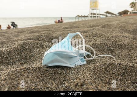 Maschera chirurgica blu lasciata dietro su una spiaggia, Spagna. Foto Stock