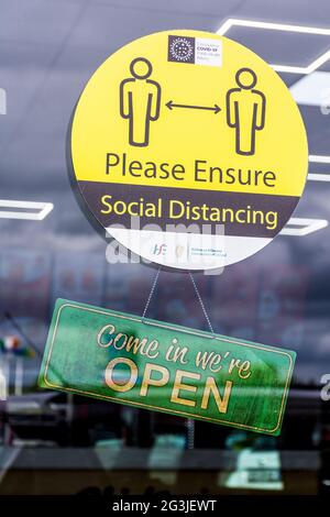 Letterkenny, Contea di Donegal, Irlanda. 16 giugno 2021. La segnaletica su un ristorante da asporto dice "come in We're Open" e un avviso sulla distanza sociale all'interno dell'hotel. Foto Stock