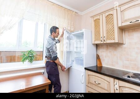 Giovane Maschio fissaggio Repairman frigorifero in cucina Foto Stock