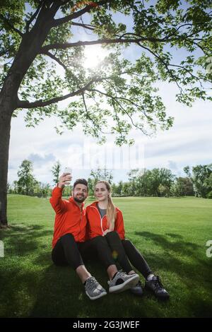 Sport l uomo e la donna che fa selfies in posizione di parcheggio Foto Stock