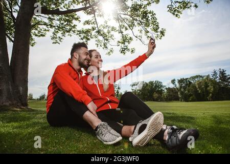 Sport l uomo e la donna che fa selfies in posizione di parcheggio Foto Stock