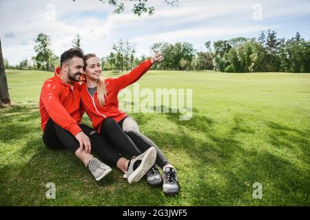 Sport l uomo e la donna che fa selfies in posizione di parcheggio Foto Stock