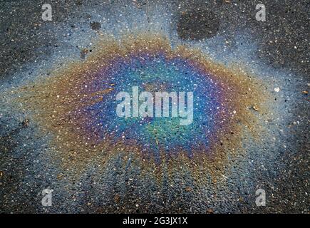 Macchia di gas colorata su asfalto umido. Questo è il tipo di macchia causata da una perdita sotto un'automobile o un camion. Foto Stock