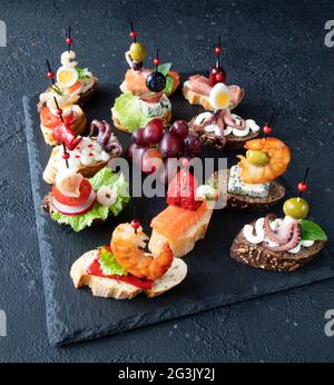 Un set di tradizionali panini con tapas spagnole a base di pesce, gamberi, calamari, polpi, salmone, uva, gorgonzola, crema di formaggio e baguette Foto Stock