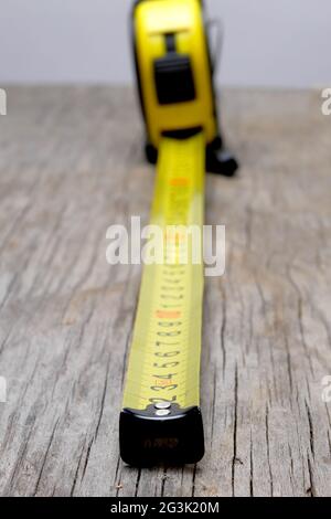 nastro di misurazione giallo esteso su tavola di legno Foto Stock