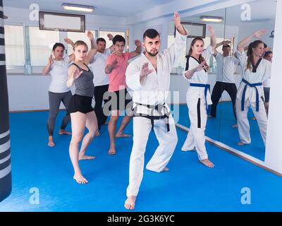 adulti che tentano di padroneggiare nuove mosse durante la lezione di karate Foto Stock