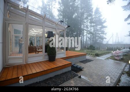 Bielorussia - 26.02.2015 - Terrazza di vetro che si affaccia sulla foresta nebbiosa. Casa propria in una foresta. Foto Stock