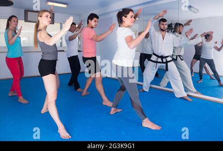 adulti che tentano di padroneggiare nuove mosse durante la lezione di karate Foto Stock