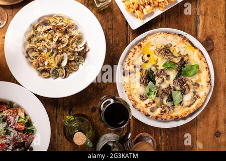 Pizza e pasta su tavola di legno con vino Foto Stock