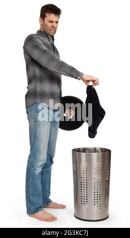 Giovane uomo che mette le calze sporche in un cesto di bucato Foto Stock