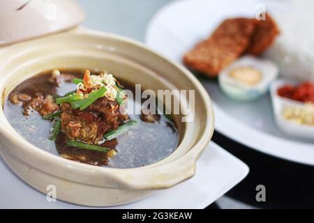 Rawon è la tradizionale zuppa di carne nera giavanese con spezie indonesiane ricche e forti, servite con germogli e uova salate Foto Stock