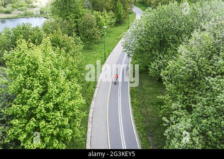 due ciclisti cavalcano le biciclette sulla pista ciclabile nel parco della città in primavera. fotografia aerea con il drone. Foto Stock