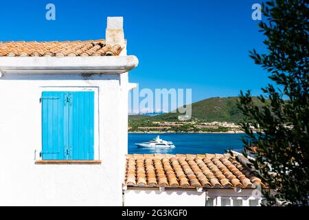 (Fuoco selettivo) splendida vista di una finestra blu chiusa su una parete bianca e di uno yacht di lusso sfocato che naviga sullo sfondo. Foto Stock