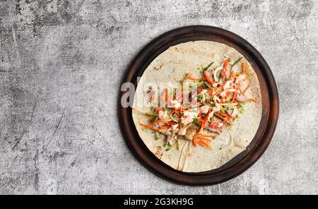 Sandwich Shawarma con ingredienti su un tagliere rotondo in legno su sfondo grigio scuro. Vista dall'alto, disposizione piatta Foto Stock