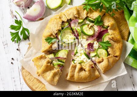 Farina di segale sana, prodotti da forno, senza glutine, cibo dietetico. Galette con zucchine, cipolle e formaggio feta su tavola di legno. Foto Stock