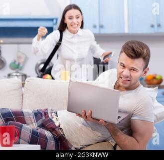 Lazy marito al lettino e sua moglie furiosa, chi va a lavorare. Foto Stock