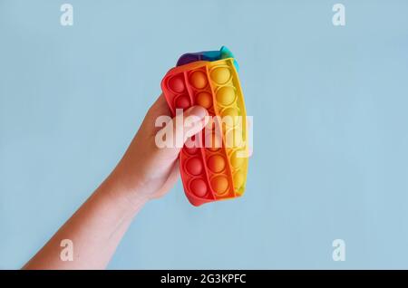 Una mano di un bambino schiacciata in mezzo giocattolo di silicone quadrato. Foto Stock