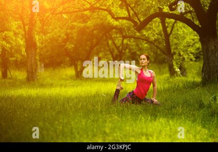 Ragazza a praticare yoga in giardino, uno zampe piccione re pongono. Foto Stock